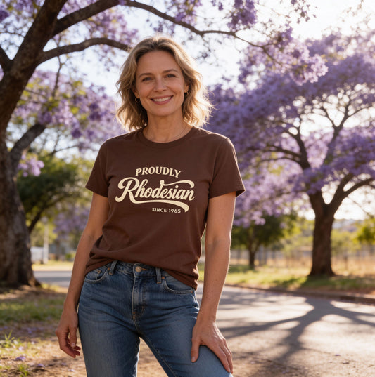 Woman wearing a brown t-shirt with 'Proudly Rhodesian' text, standing in front of Jacaranda trees.