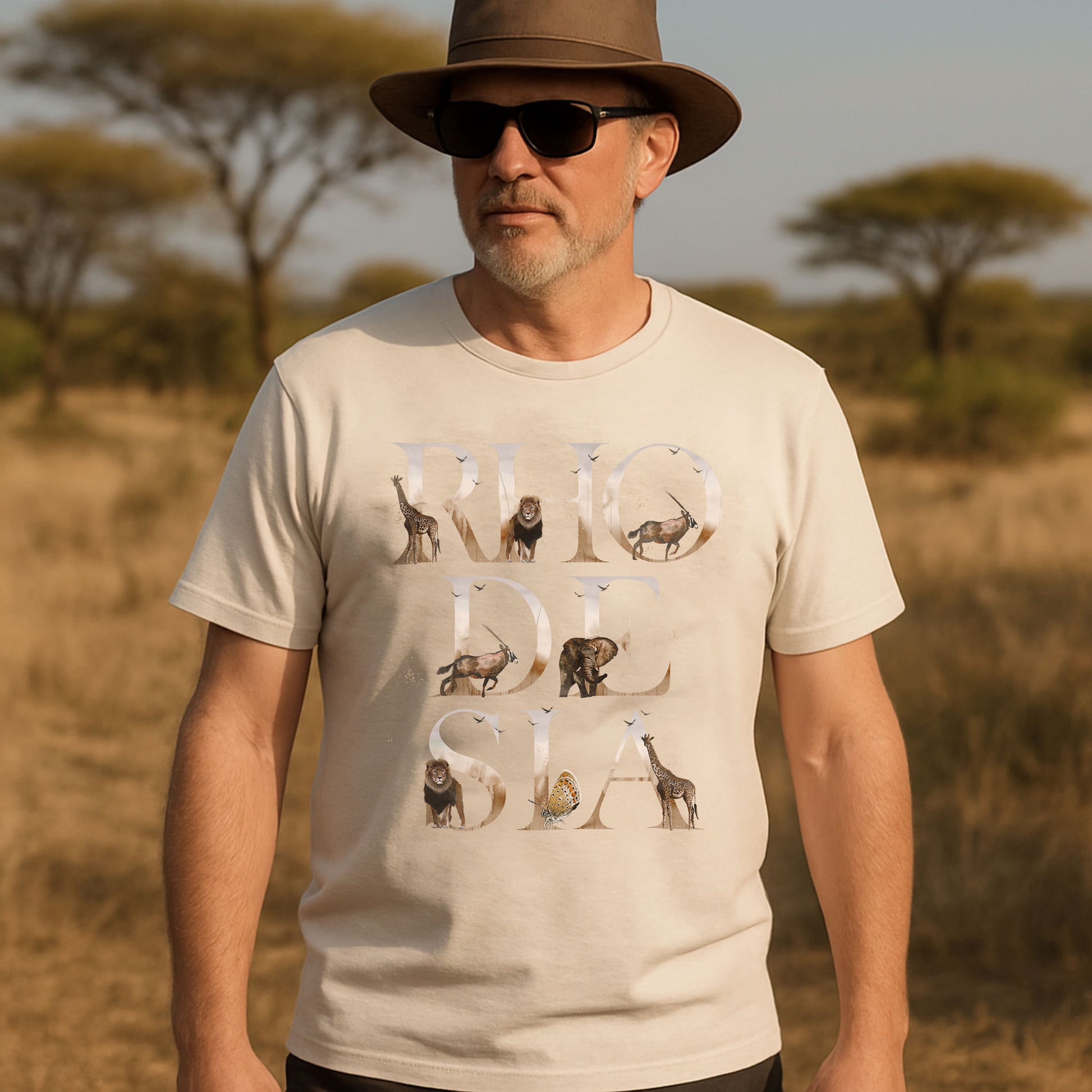 Man wearing a beige t-shirt with animal illustrations and text, standing in a savannah setting.
